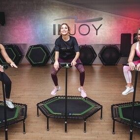 Drei Frauen trainieren gemeinsam auf Fitness-Trampolinen in einem modernen Fitnessstudio.