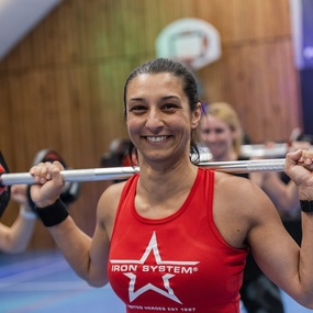 Frau beim Fitness-Training mit Langhantel in Sporthalle, Gewichtheben und Krafttraining.